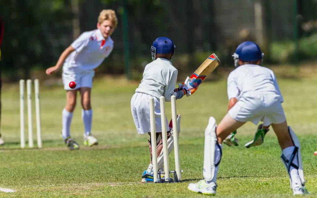 Children playing junior cricket, batting, bowling and wicketkeeping